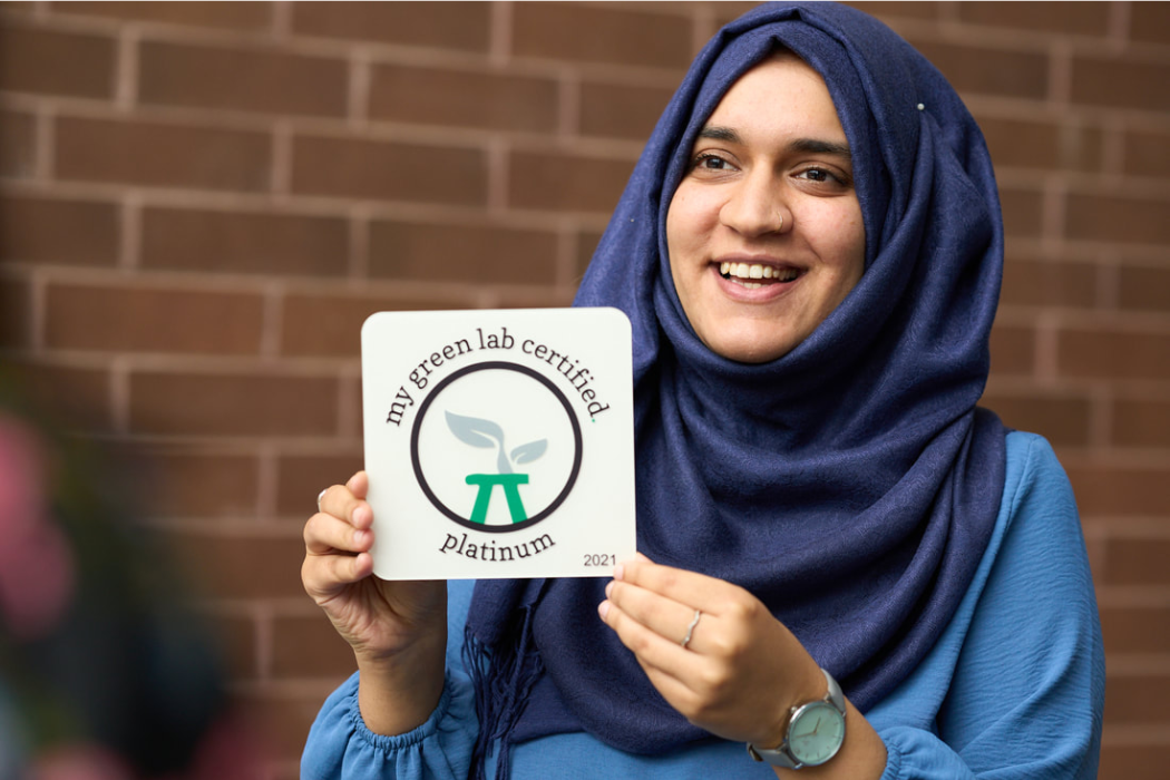 girl wearing a hijab holding a plaque showcasing my green lab certification platinum level