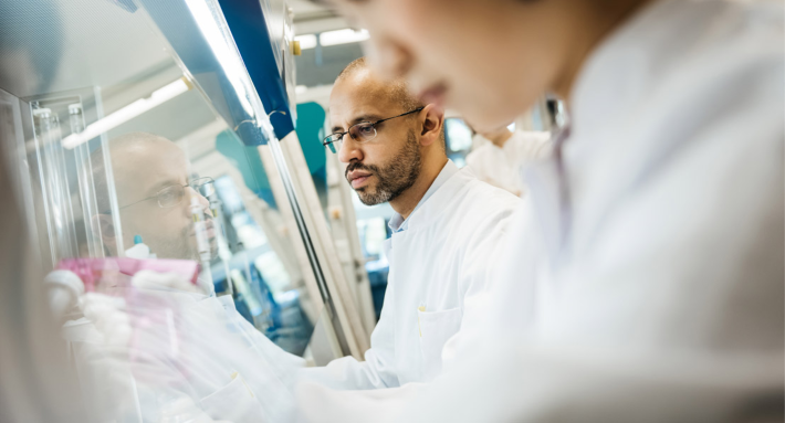 Man and women in white lab coats working in the lab to create more sustainable operations